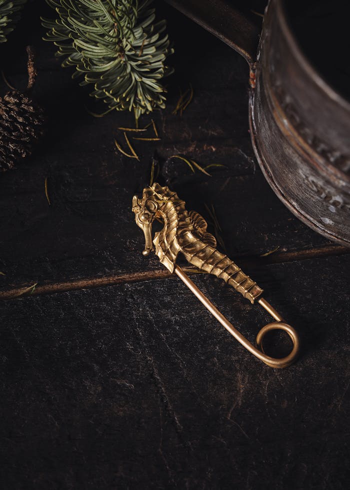 services-03 A detailed handcrafted seahorse jewellery pin with rustic metalwork, set against a dark wooden backdrop.