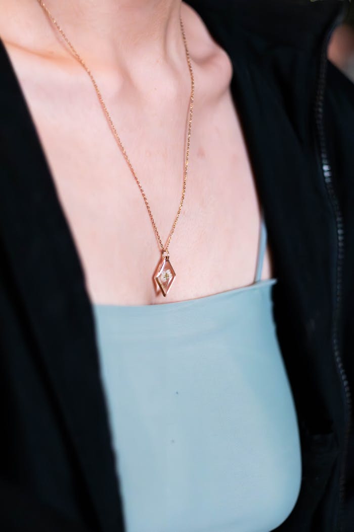 gallery-3 Close-up of a gold necklace worn by a woman, showcasing elegance and style.