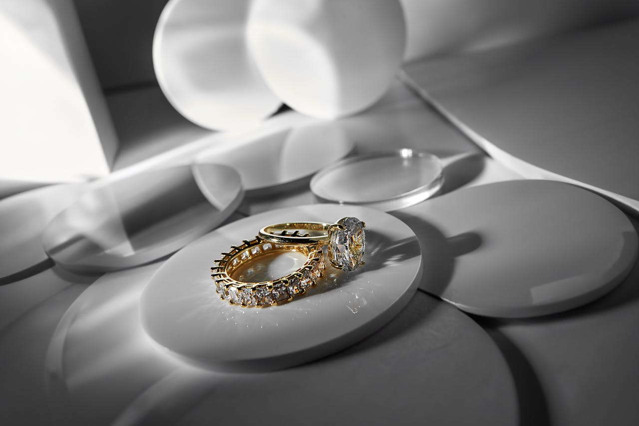 hero-img-01 Close-up of elegant gold and diamond rings on a modern abstract surface, showcasing luxury style.
