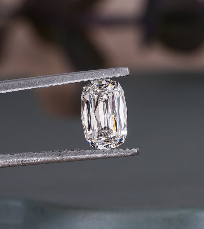 gallery-4 Close-up of a sparkling lab-grown diamond held by tweezers, showcasing intricate cuts.