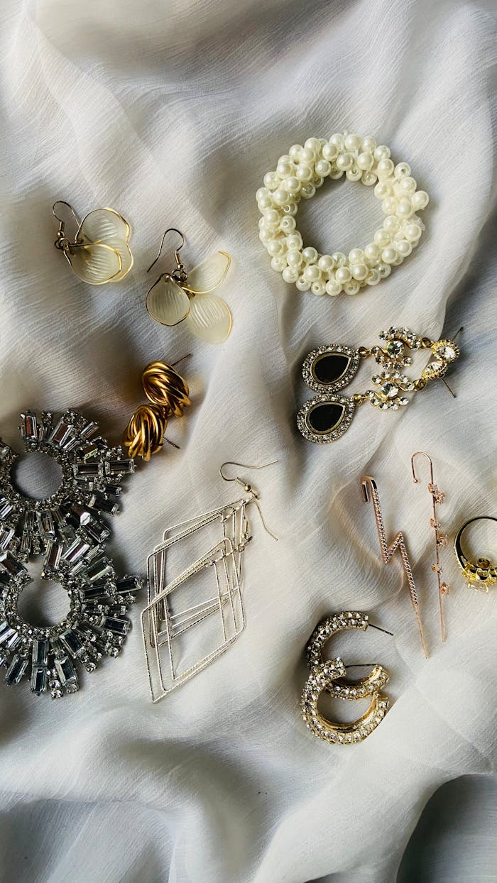 services-04 A stylish display of various earrings and jewelry pieces on a white fabric background.