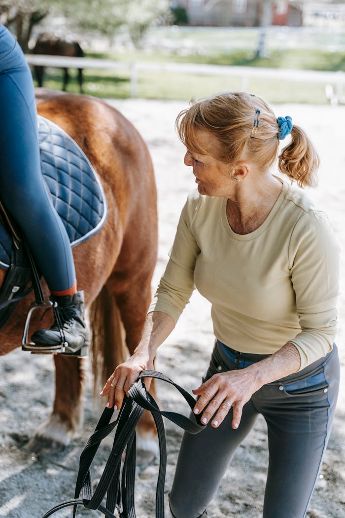 services-03 Woman assisting rider during equestrian training session outdoors, showcasing skill and teamwork.